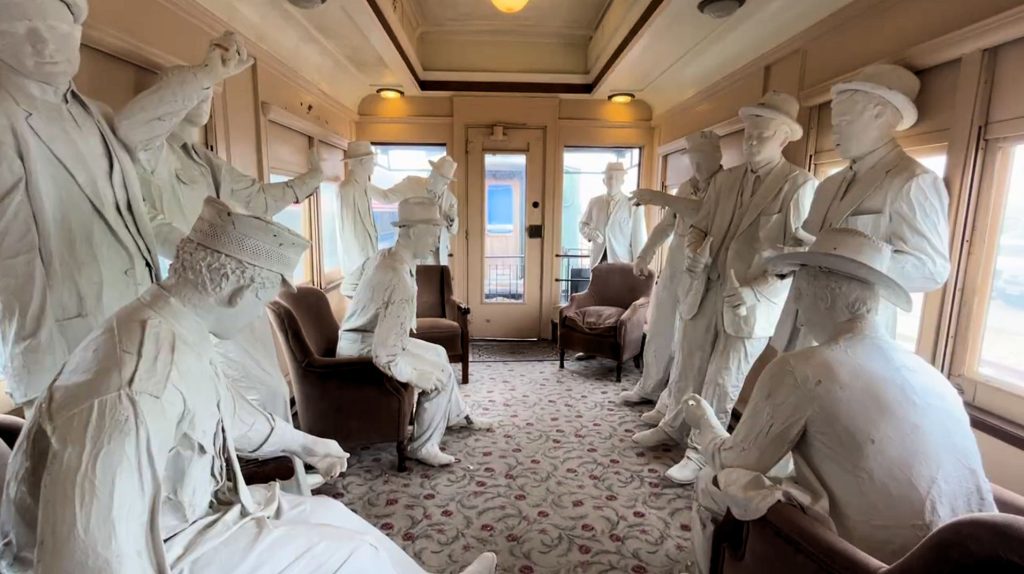 Life-size white statues inside vintage train car