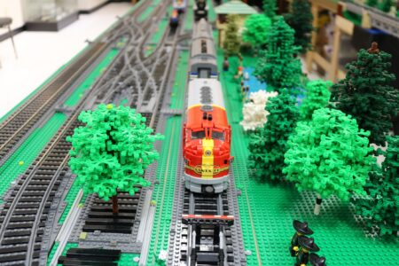 Red model train on LEGO track with trees